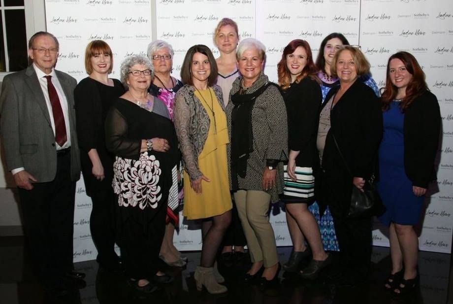Three women are standing next to each other holding a plaque.