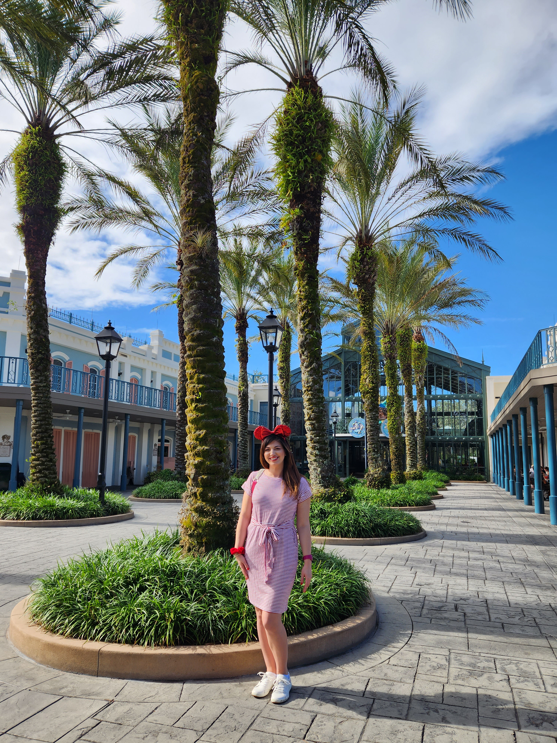 women standing in front of palm trees A woman in a pink dress is standing in front of a row of palm trees.