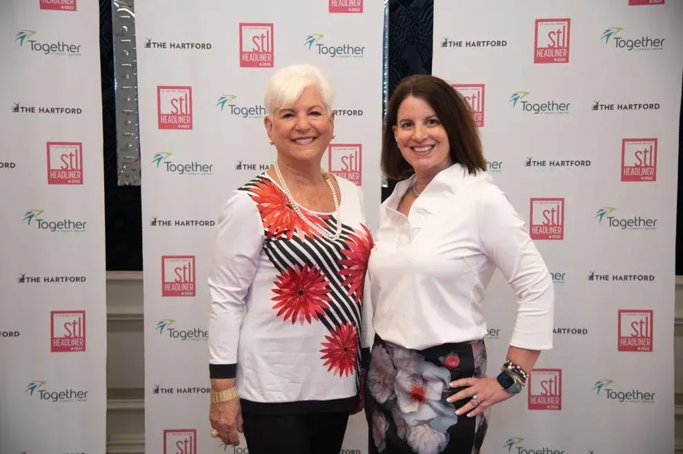two women posing before backdrop