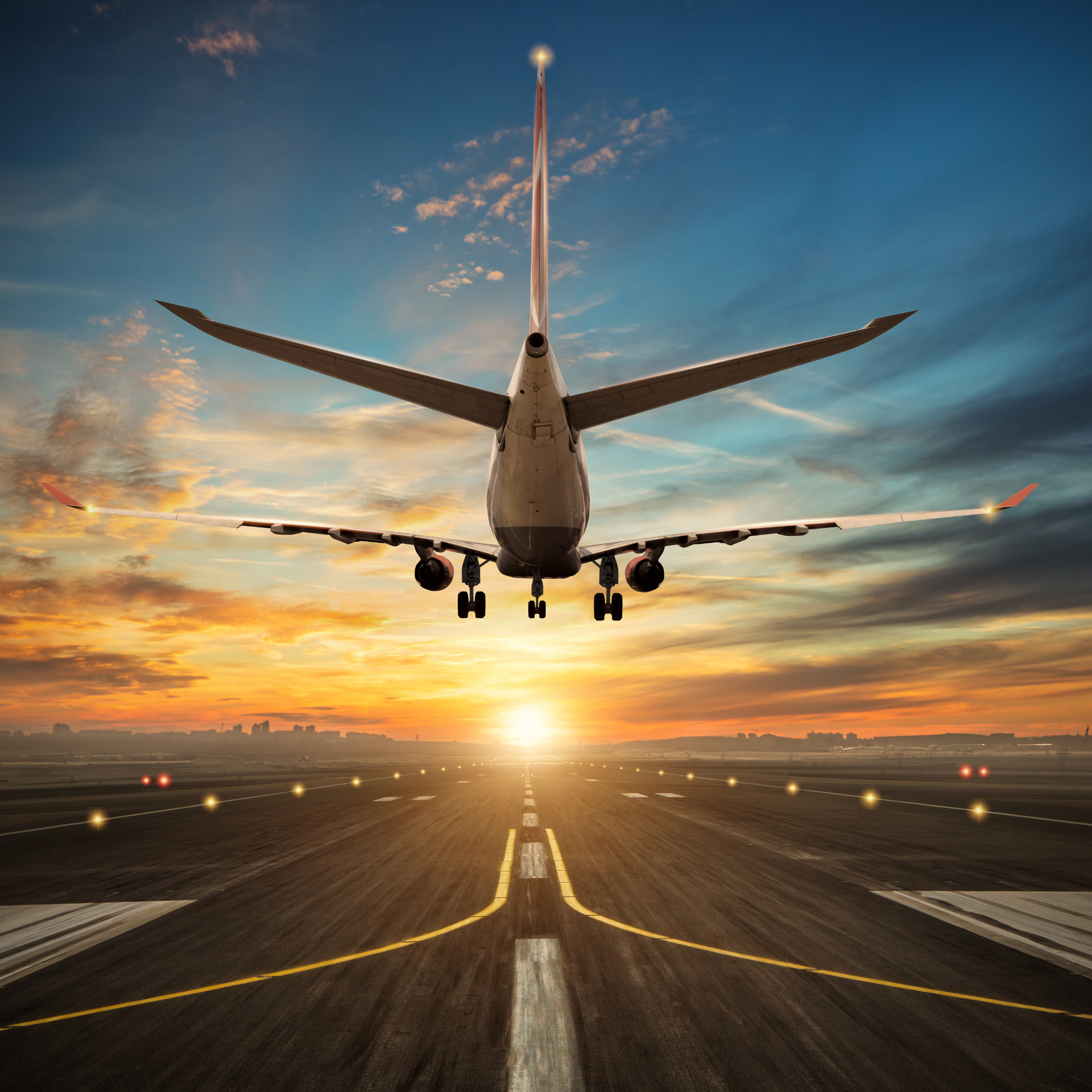 An airplane is taking off from an airport runway at sunset.