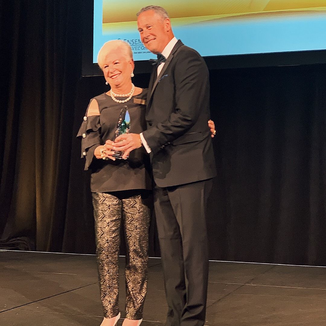 A man and woman are standing on a stage holding an award.