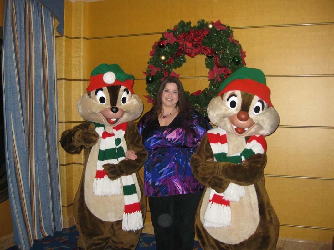women beside statue chipmunks A woman poses with chipmunks wearing christmas hats and scarves