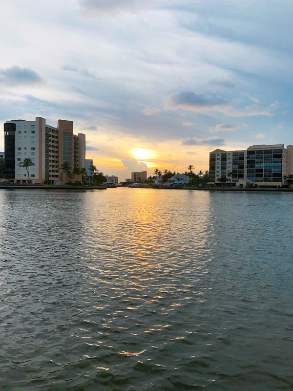 A sunset over a body of water with buildings in the background.