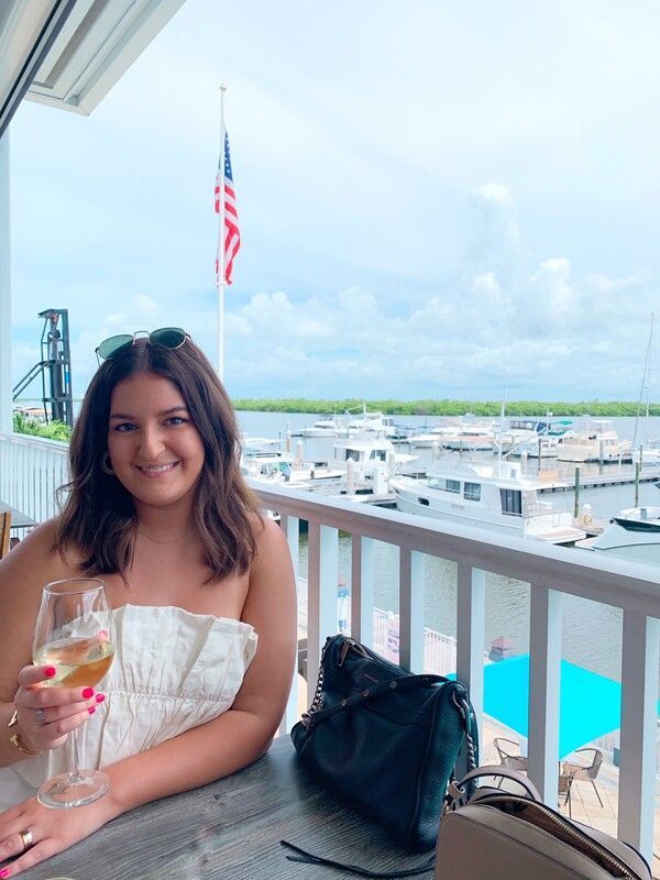 A woman is sitting at a table holding a glass of wine.