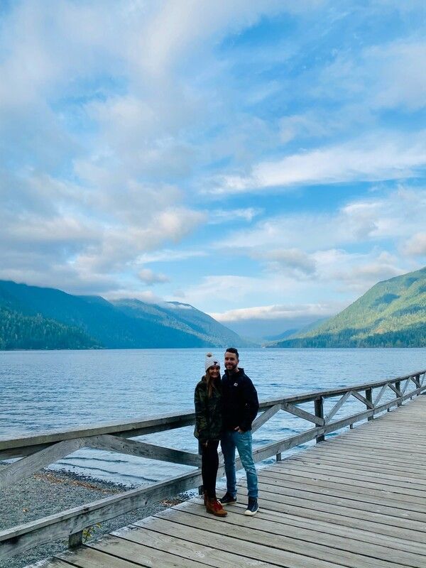 A man and a woman are standing on a pier overlooking a lake.