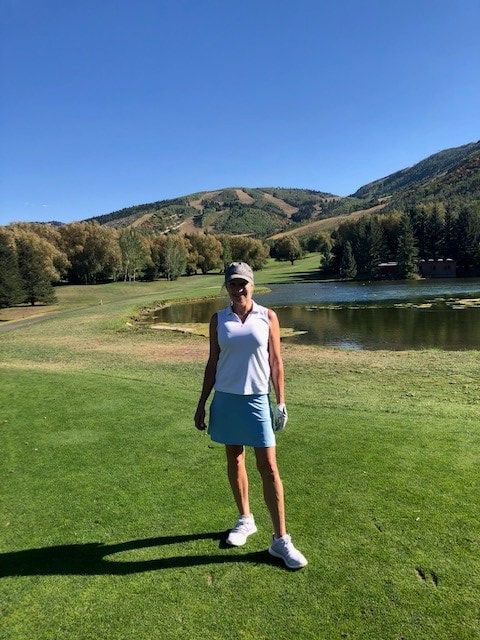 A woman is standing on a golf course next to a lake.