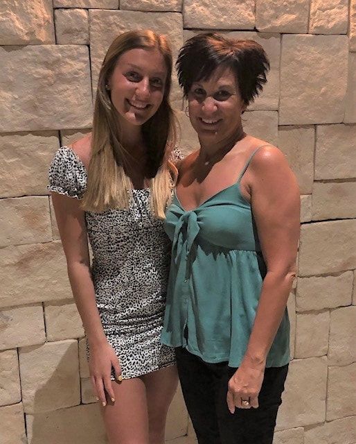 Two women posing for a picture in front of a brick wall