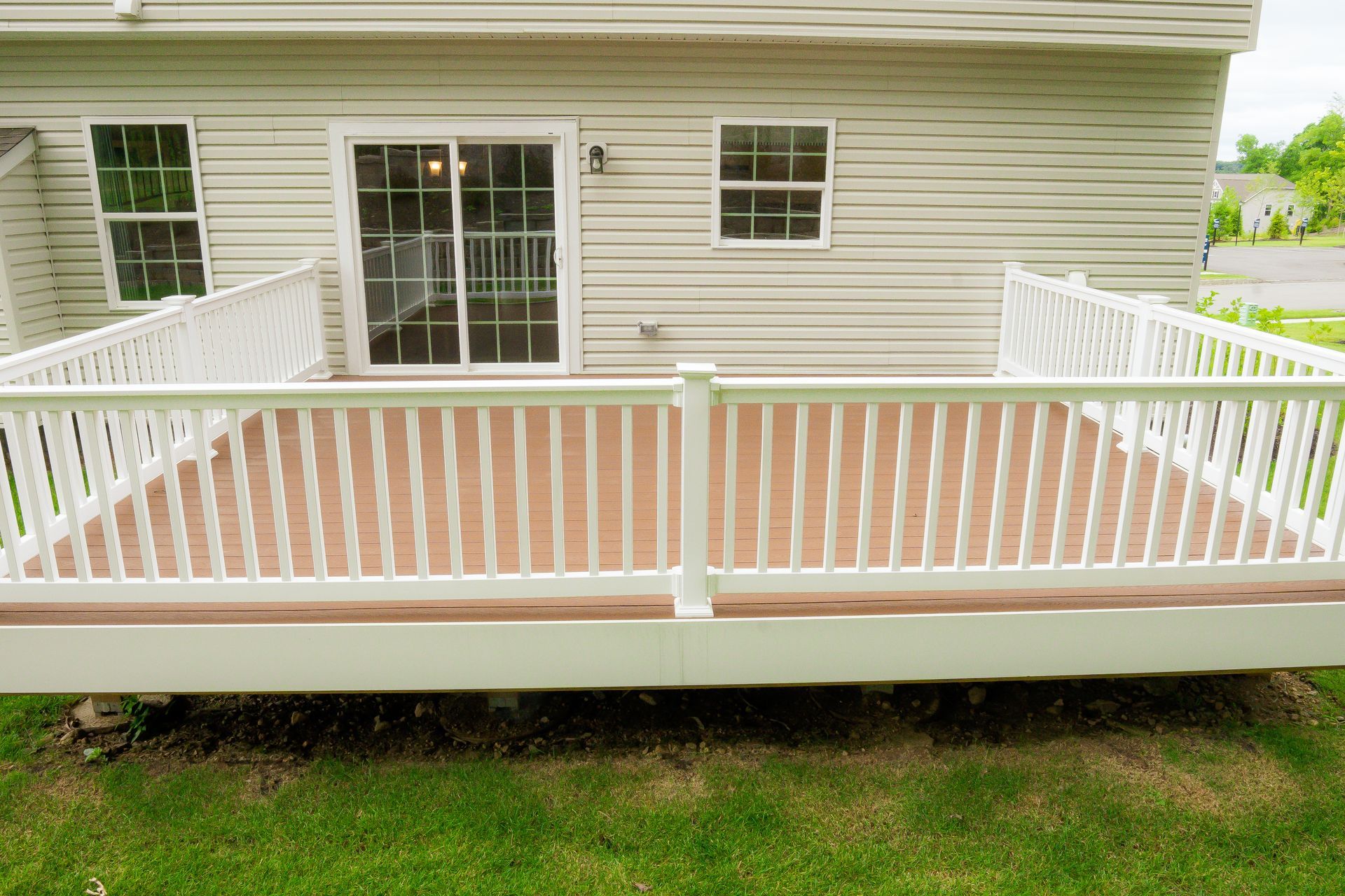 White backyard deck with railings and sliding glass door on a house