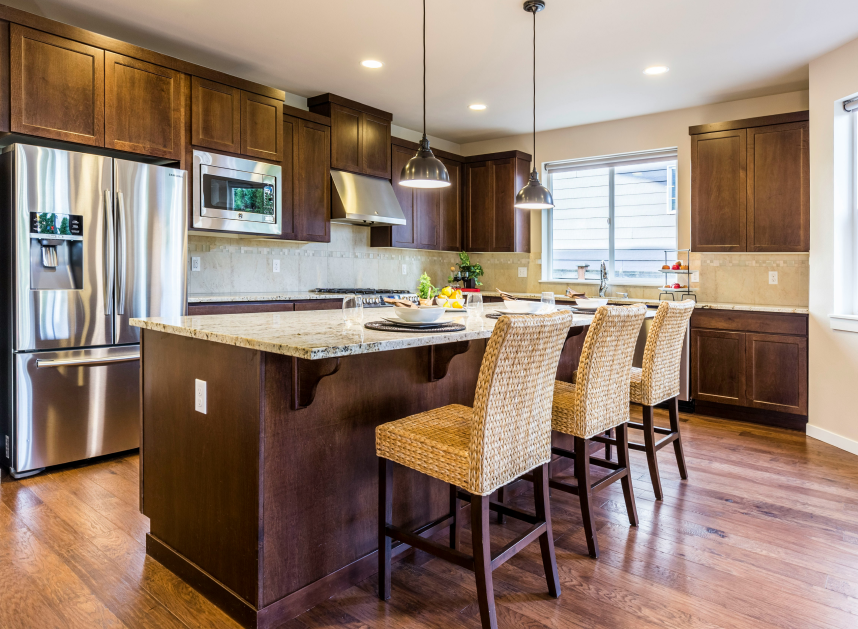 Modern kitchen with stainless steel appliances, dark wood cabinets, and a granite island with stools