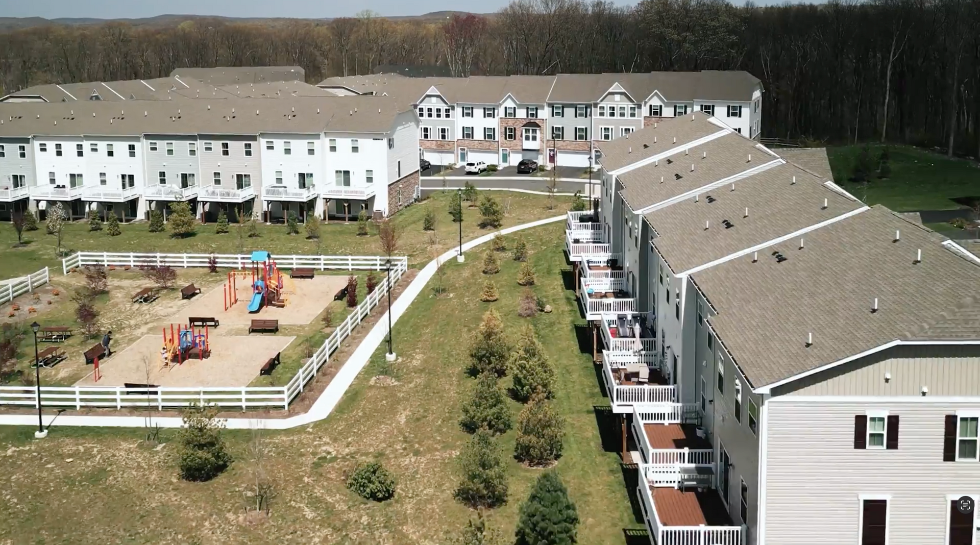 Apartment complex with playground, walkway, and rows of white buildings on a hillside