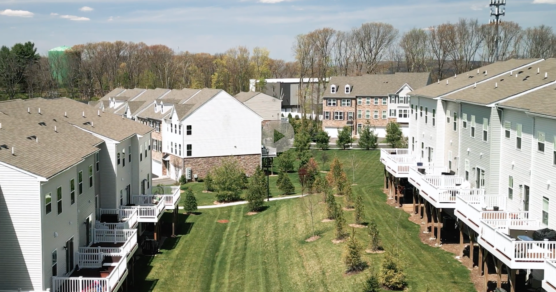 Apartment buildings lining a grassy courtyard with trees and blue sky