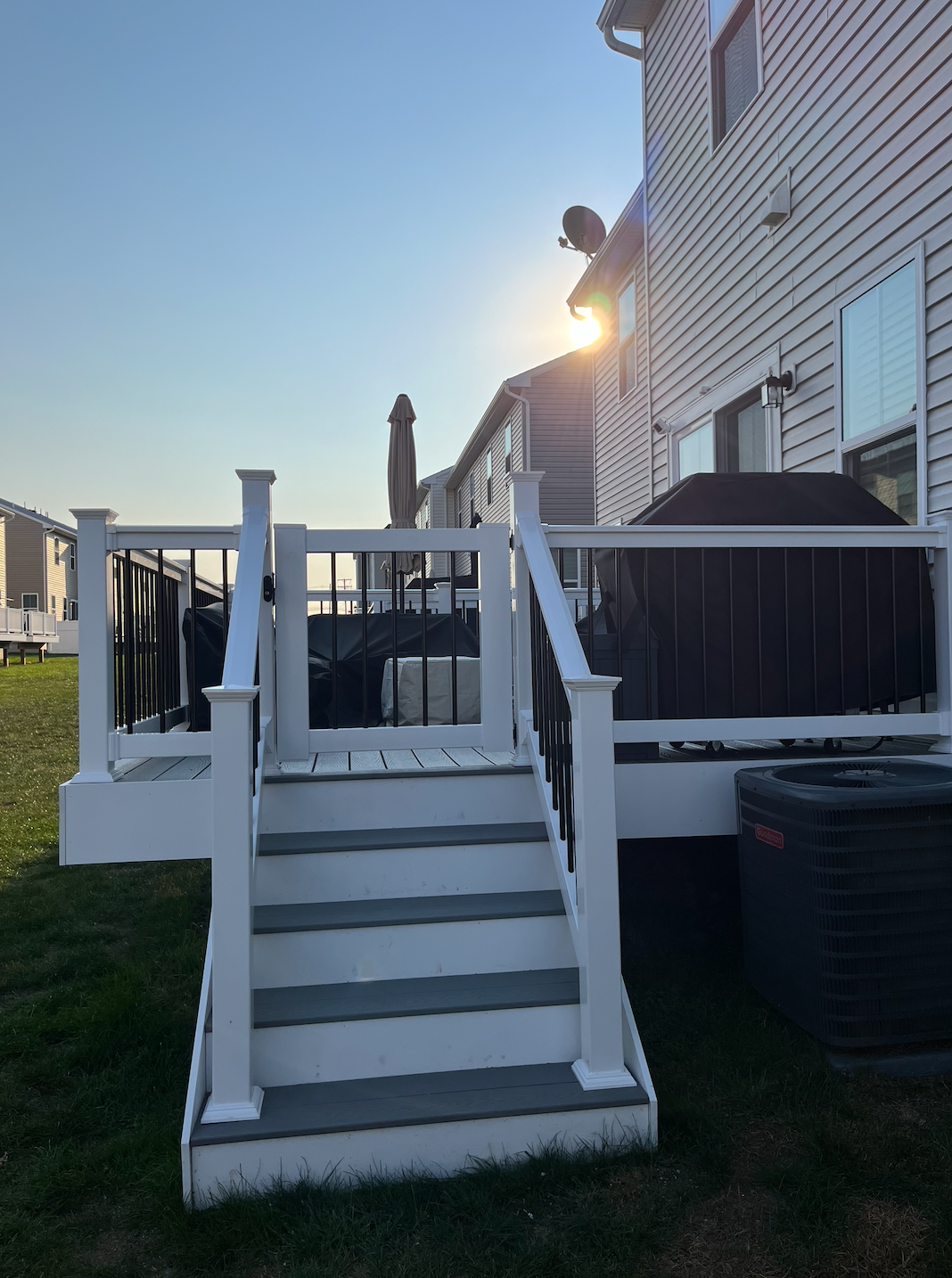 Back steps with white railings leading to a deck on a house at sunset