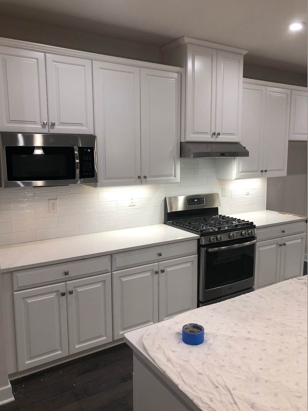 Bright modern kitchen with white cabinets, black appliances, and a marble island countertop