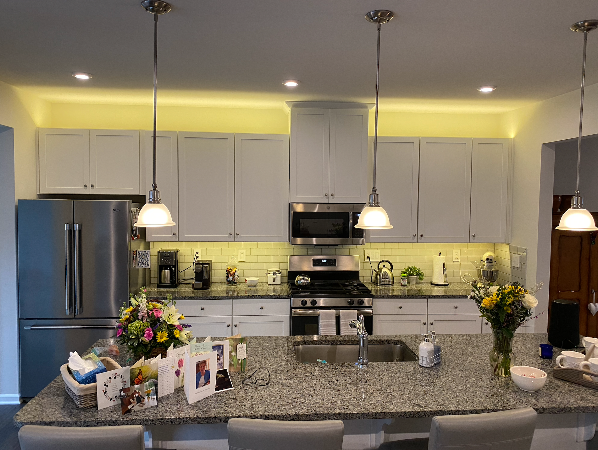 Modern kitchen with white cabinets, granite island, stainless appliances, and flowers on the counter