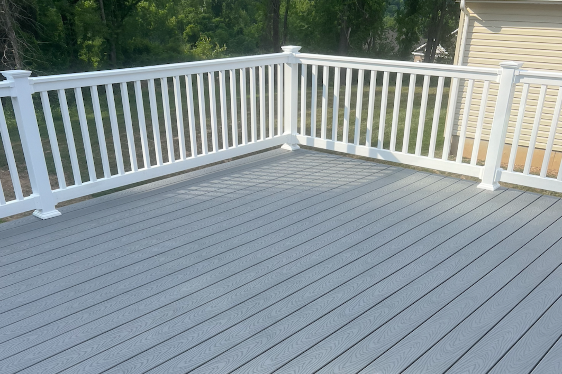 Gray composite deck with white railing overlooking trees and greenery
