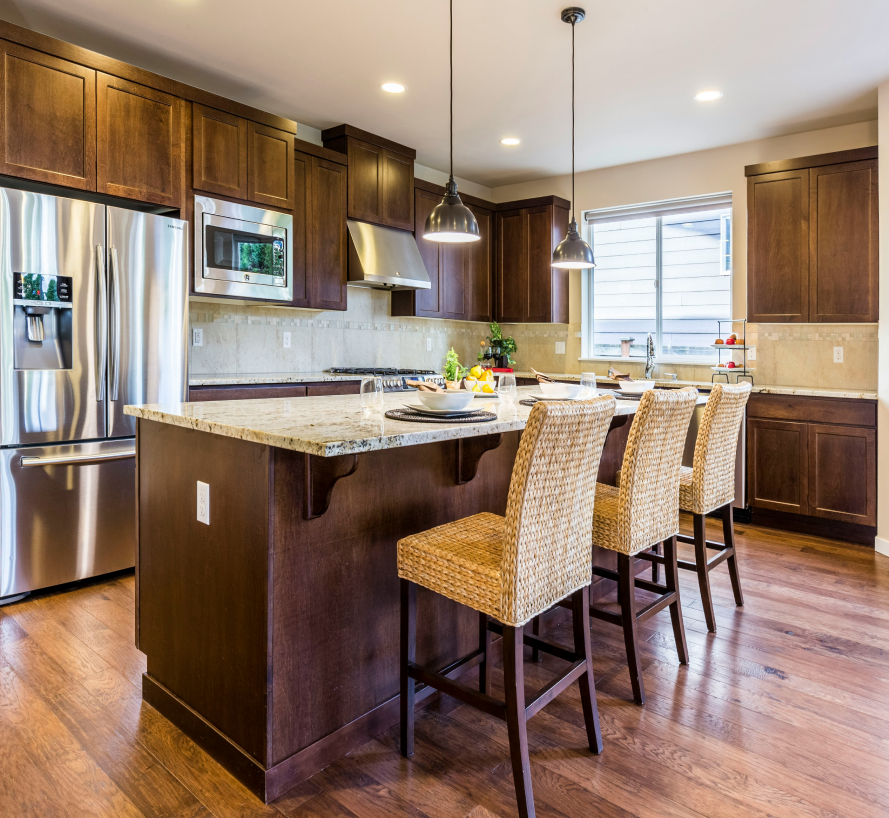 Modern kitchen with dark wood cabinets, stainless steel appliances, and an island with wicker stools