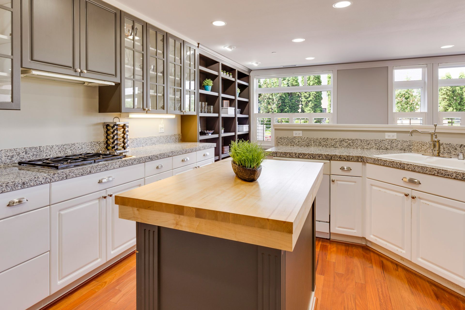 Bright modern kitchen with white cabinets, granite counters, and a large wooden island centered in the room