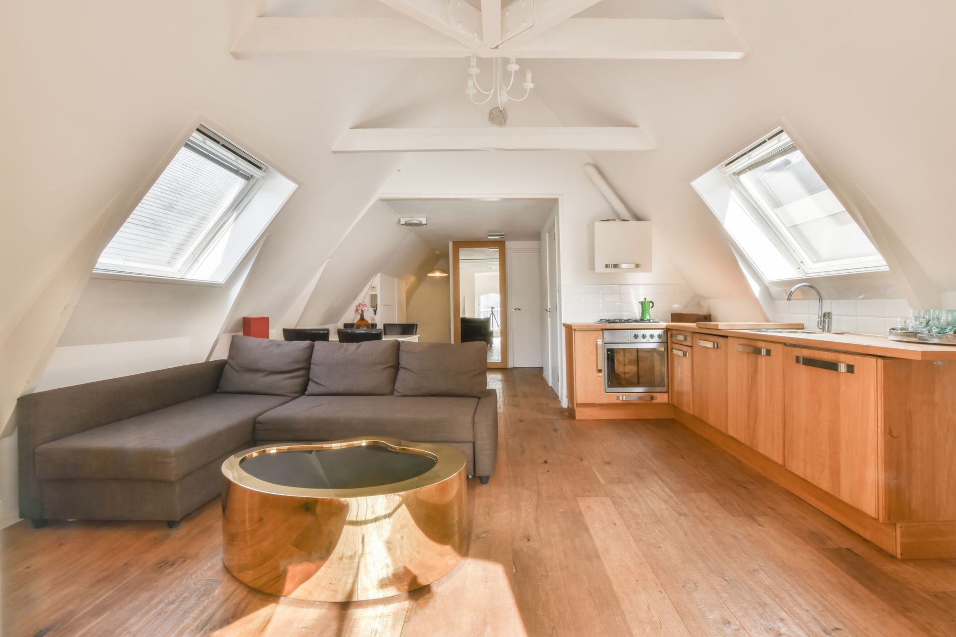 Loft living room with gray sectional, wood floor, skylights, and a kitchen counter on the right