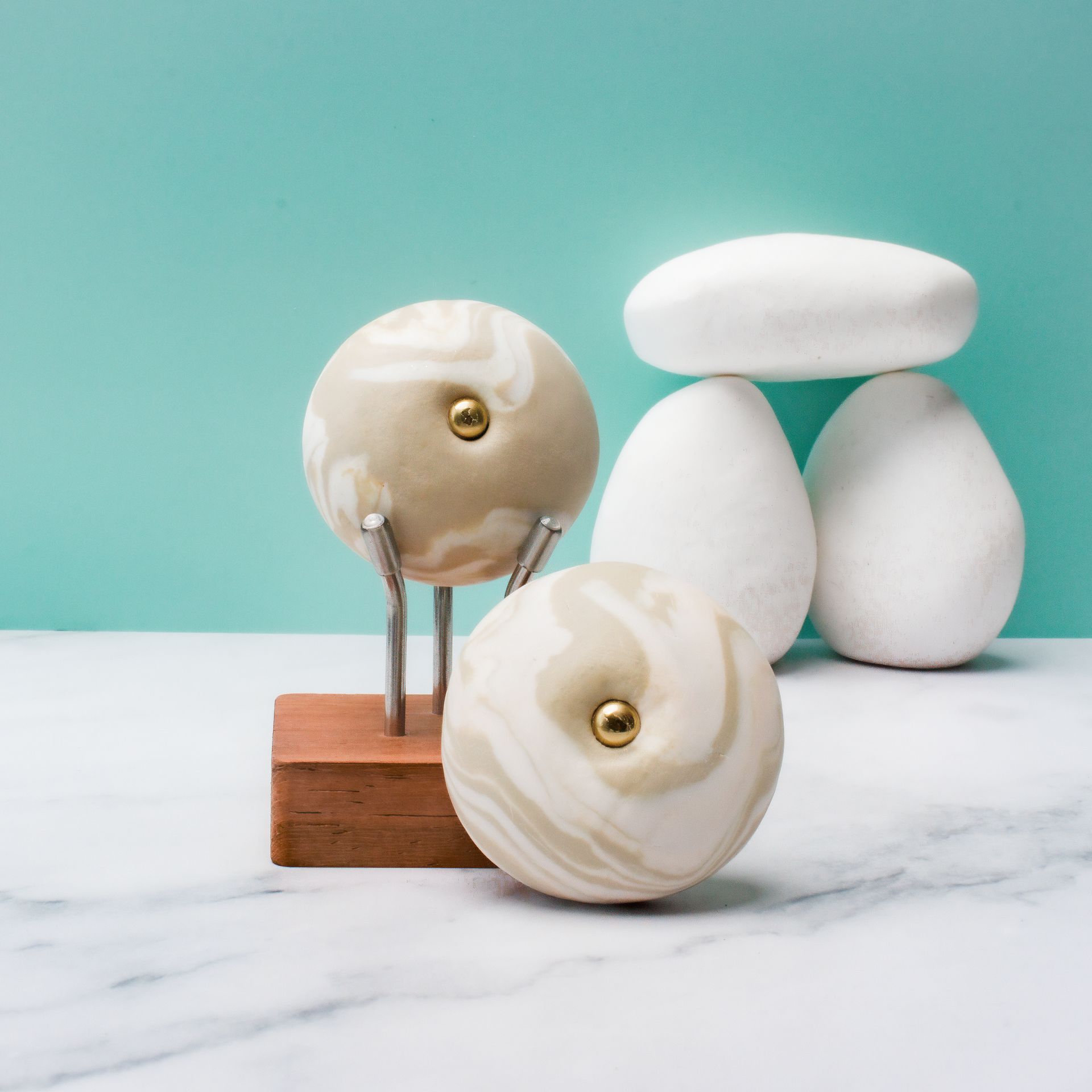 Decoratieve witte keramische kerstballen en stenen vormen op een marmeren ondergrond met een turquoise achtergrond.