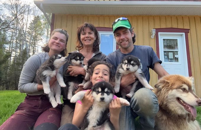 Un homme portant une veste North Face tient un bébé et un chien