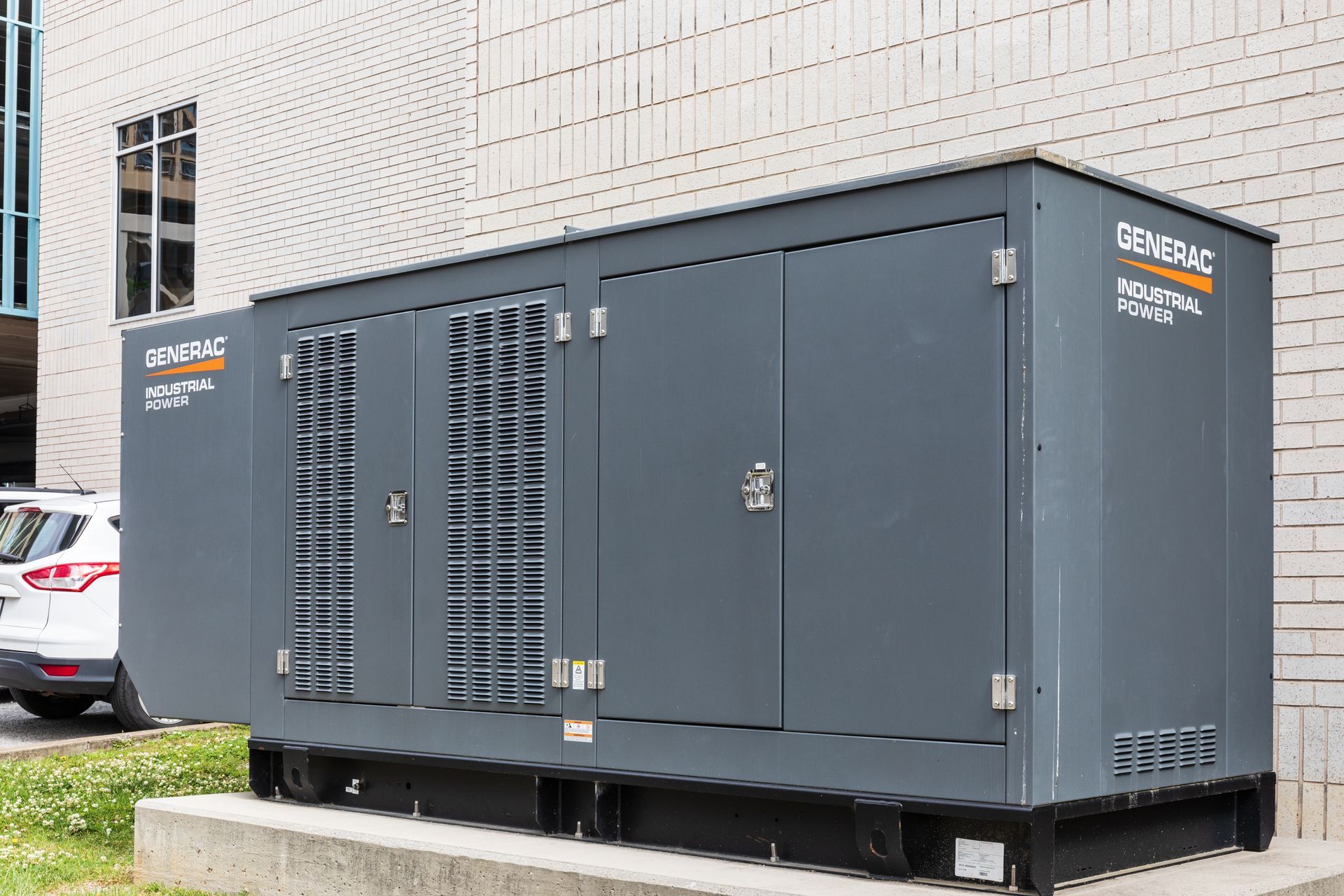 A generator is sitting in front of a brick building.