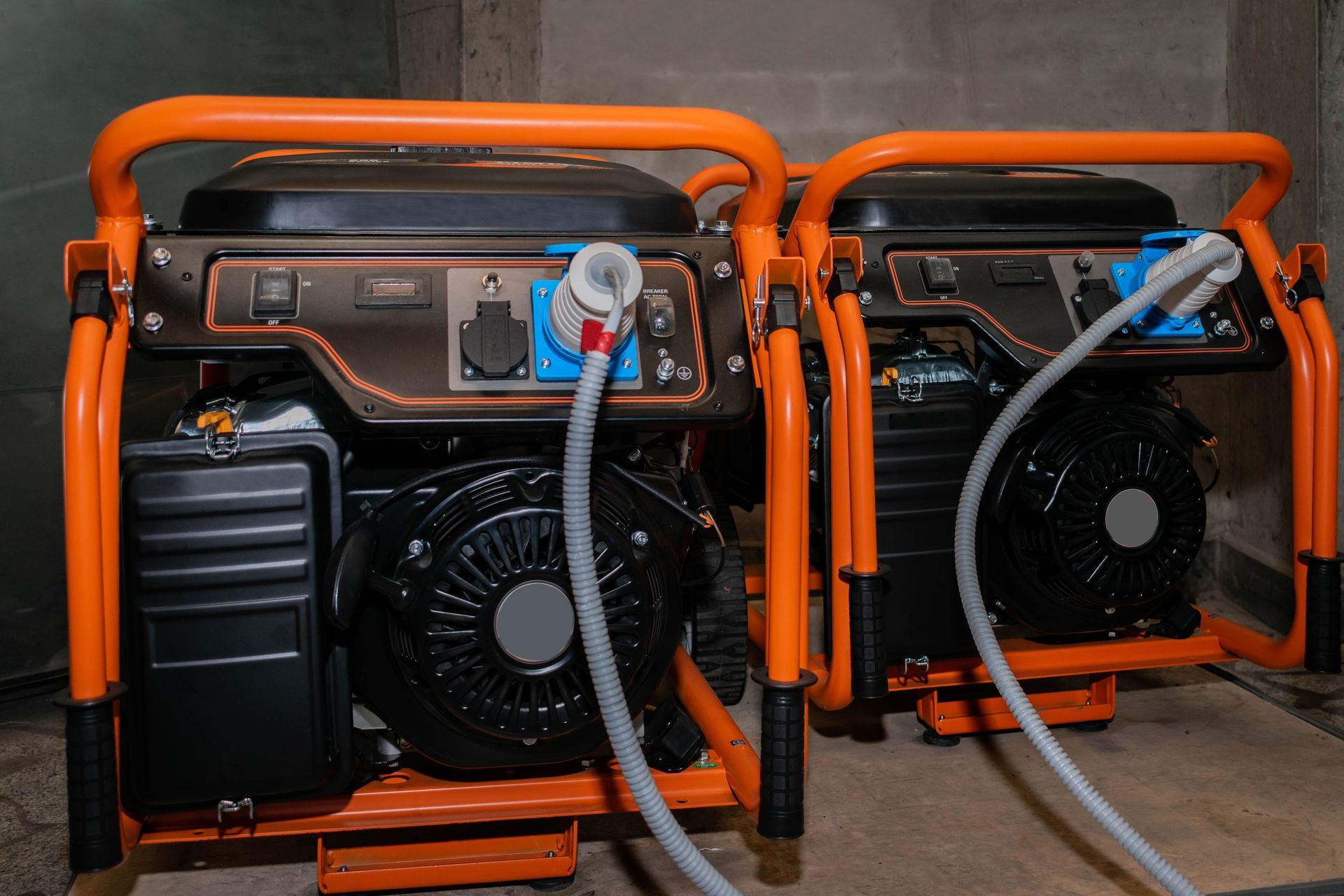 Two orange generators are sitting next to each other in a room.