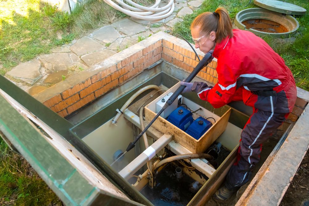 A Woman is Cleaning a Septic Tank With a Vacuum Cleaner — Accredited Plumbing in Kings Point, NSW