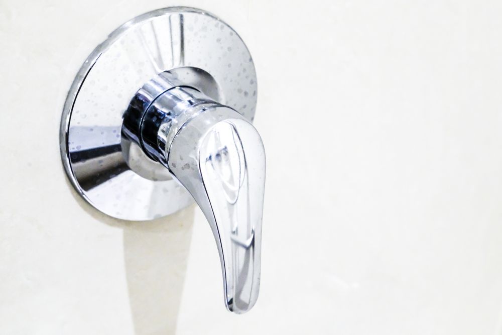 A Close Up of a Chrome Shower Faucet on a White Wall — Accredited Plumbing in Manyana, NSW