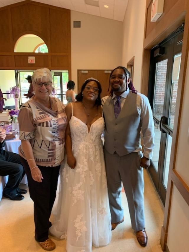 Woman in wedding dress with two people indoors.