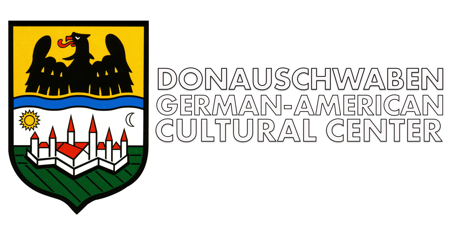 Logo of Donauschwaben German American Cultural Center. Shield with crest of figures, castle, and text.