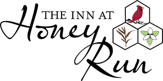 Logo for The Inn at Honey Run, includes name in script font and a cardinal in a honeycomb.
