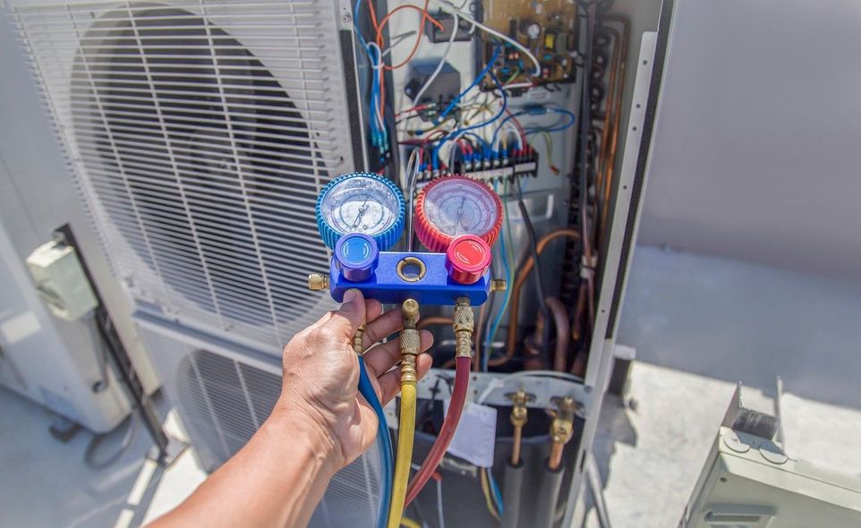 A person is working on an air conditioner with a gauge.