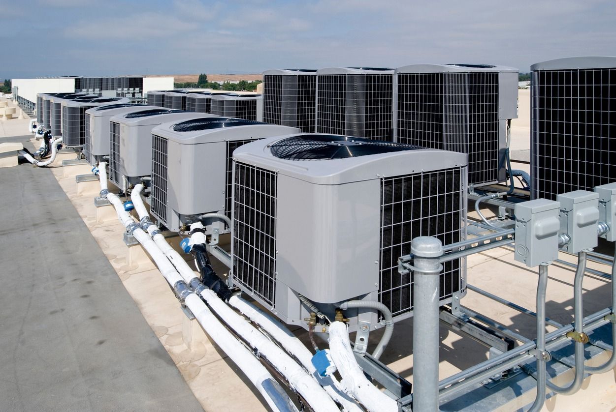 A row of air conditioners are sitting on top of a building
