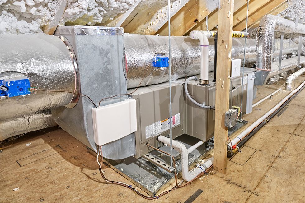 A large air conditioner is sitting in the attic of a house.