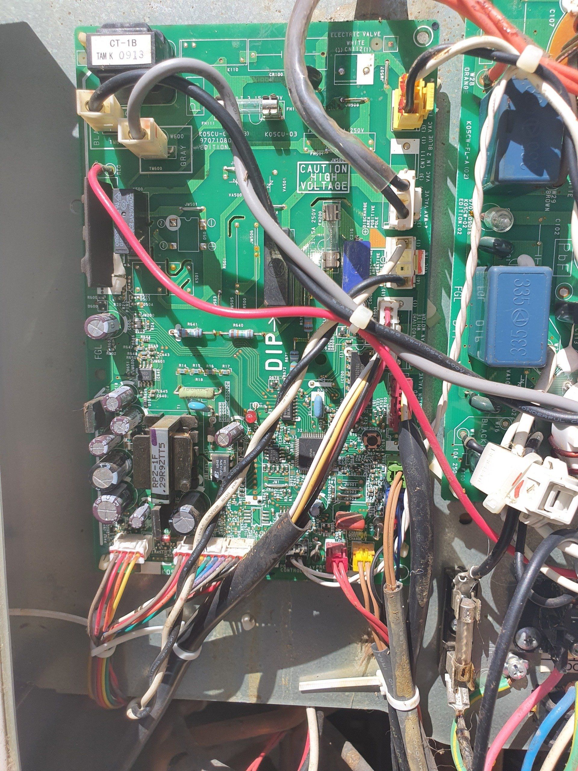 Close-up of a circuit board with tangled wires and connectors inside an electronic device cabinet