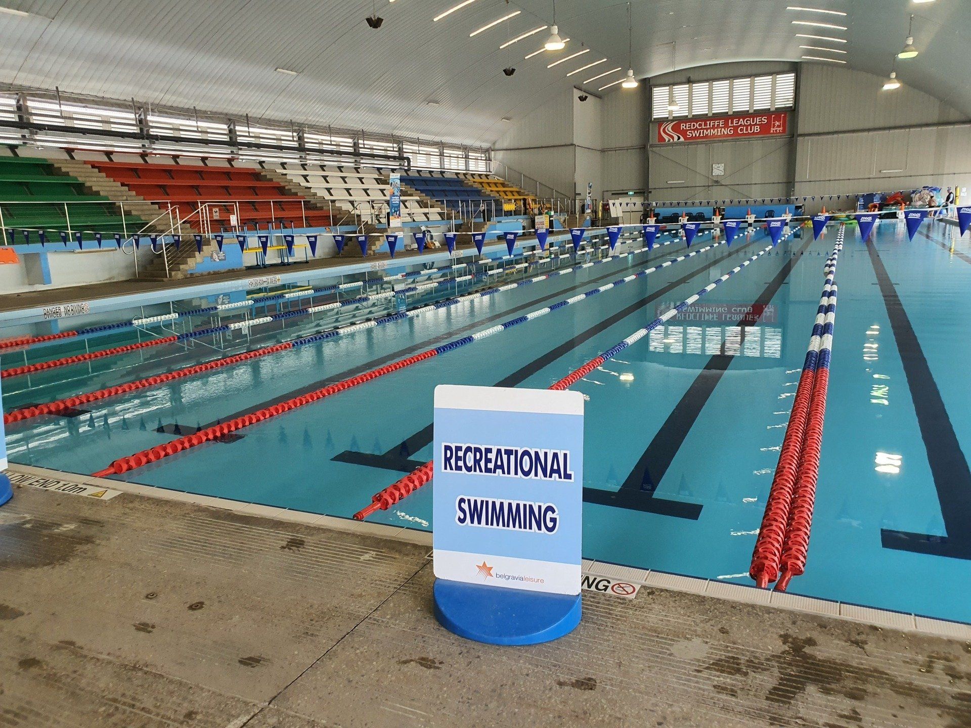 Indoor swimming pool with lanes and a “Swim” sign in the foreground