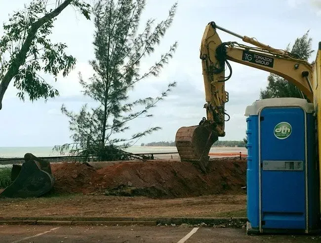 Yellow Excavator Beside a Blue Portable Toilet — Darwin Toilet Hire in Rosebery, NT