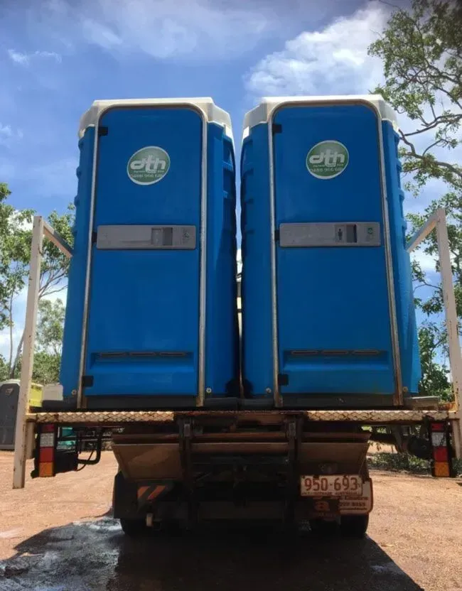 Two Blue Portable Toilets Secured on the Back of a Flatbed Truck Outdoors — Darwin Toilet Hire in Rosebery, NT