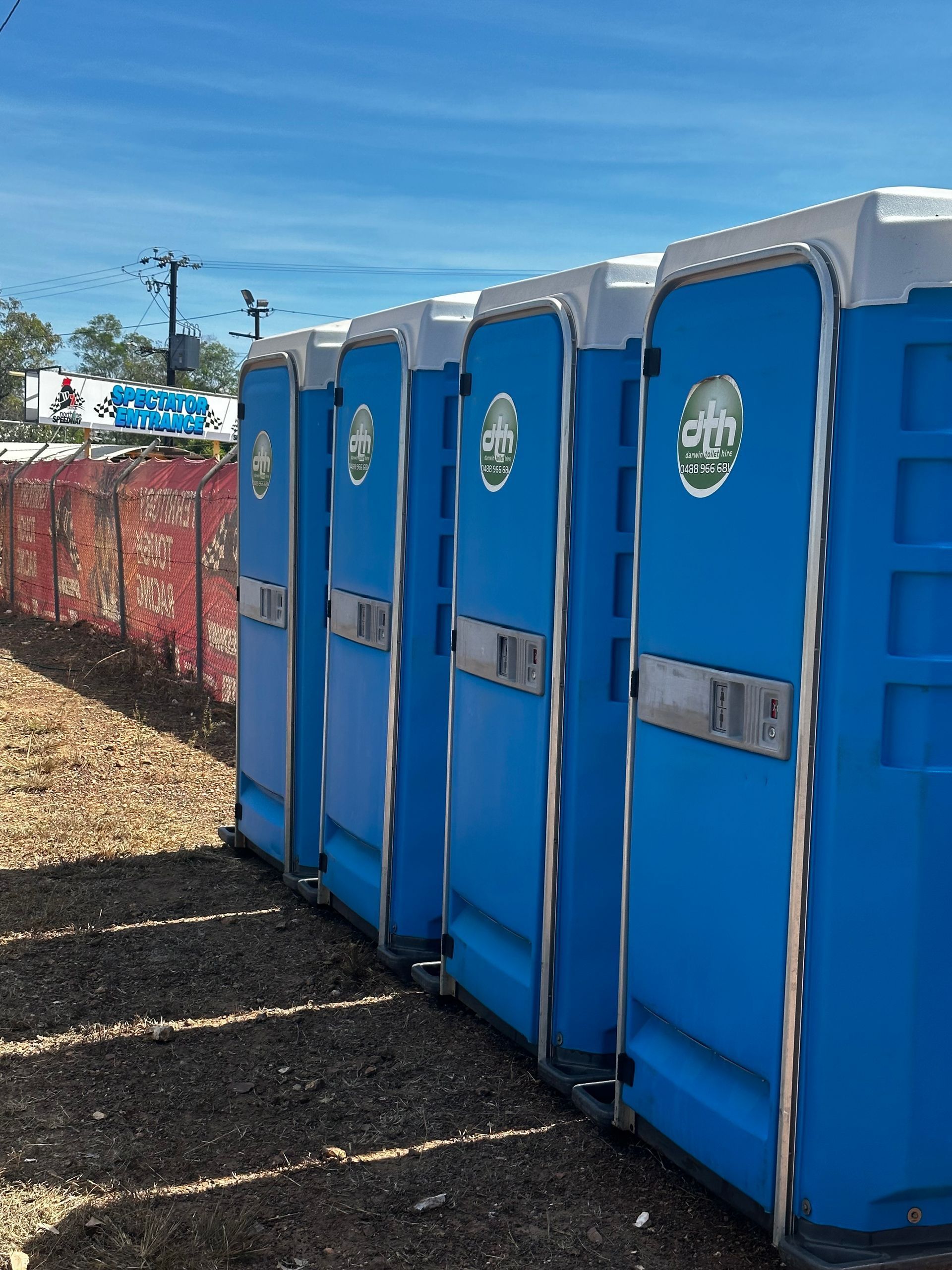 Row of Blue Portable Toilets Beside a Dirt Path at an Outdoor Event — Darwin Toilet Hire in Rosebery