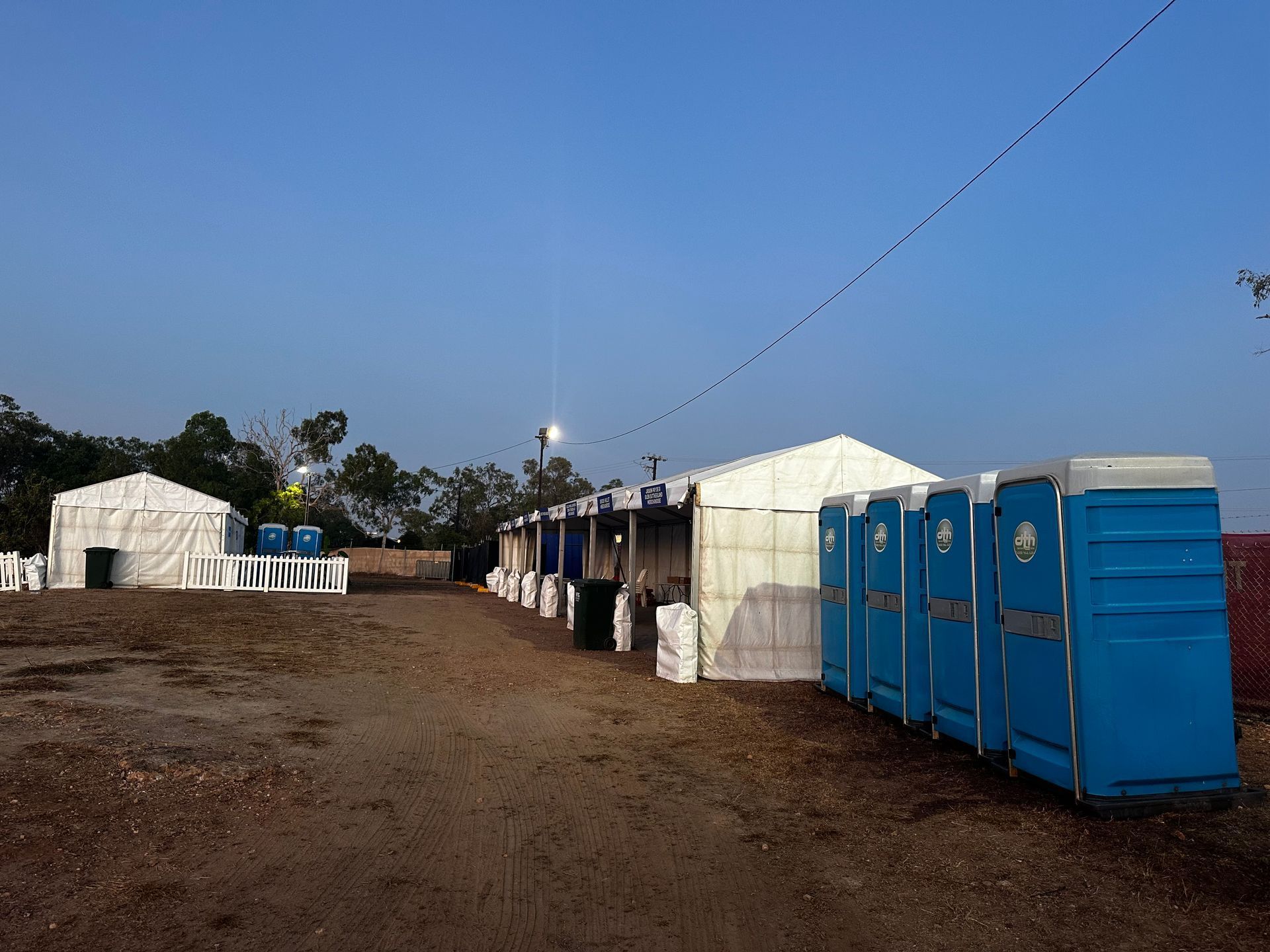Portable Toilets and Tents Set Up at a Dirt Campsite at Dusk — Darwin Toilet Hire in Rosebery, NT