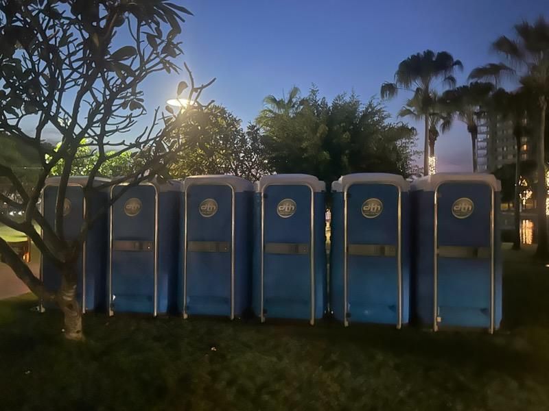 Row of Blue Portable Toilets in a Grassy Area at Dusk — Darwin Toilet Hire in Rosebery, NT
