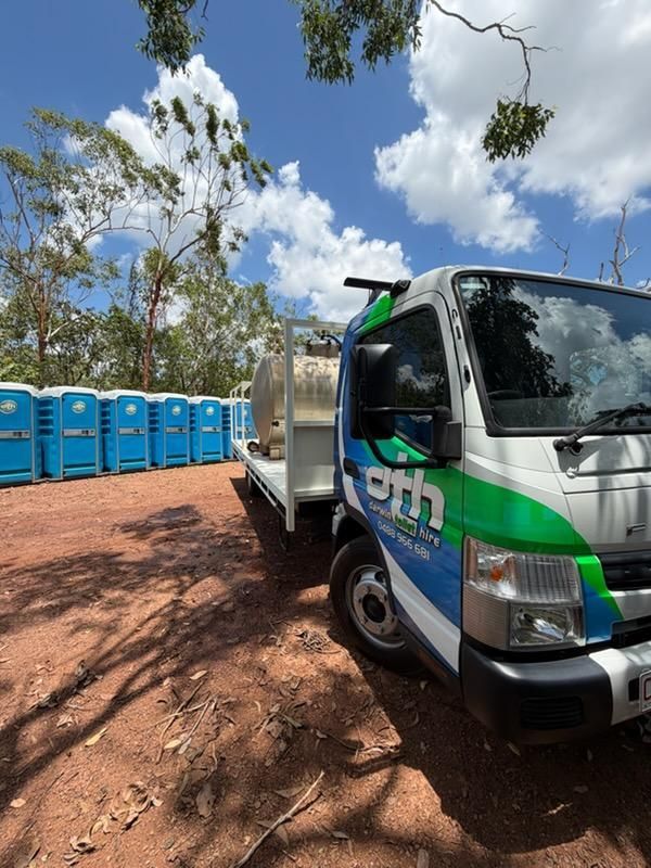 Blue Portable Toilets Beside a White-and-green Utility Truck on a Red Dirt Roadside — Darwin Toilet Hire in Katherine, NT