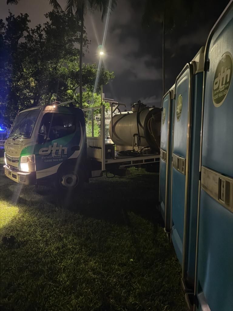 Two Trucks Parked at Night on a Grassy Roadside, Lit by Headlights — Darwin Toilet Hire in Katherine, NT