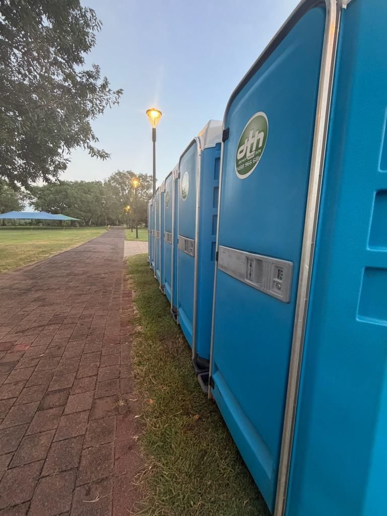 Blue Portable Toilets Beside a Brick Path at Dawn, With Streetlamps and Trees — Darwin Toilet Hire in Palmerston, NT