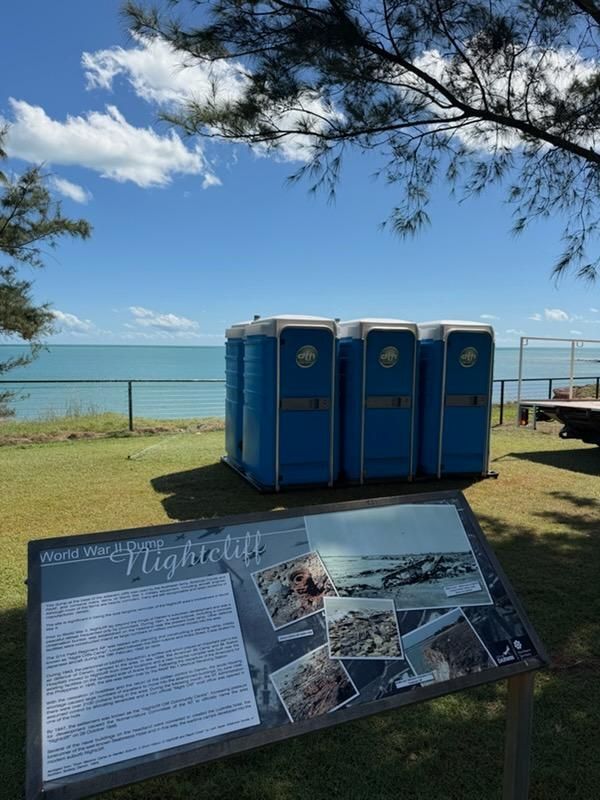 Beachside Sign Beside Blue Portable Toilets Under Trees — Darwin Toilet Hire in Rosebery, NT