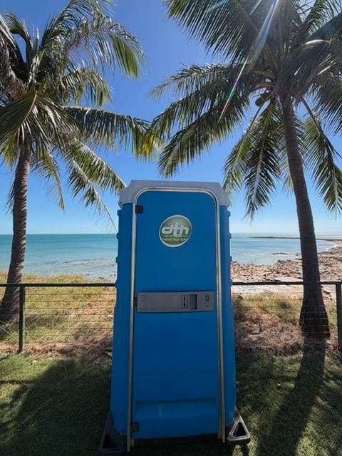 Blue Portable Restroom on a Beach With Palm Trees and Ocean — Darwin Toilet Hire in Rosebery, NT