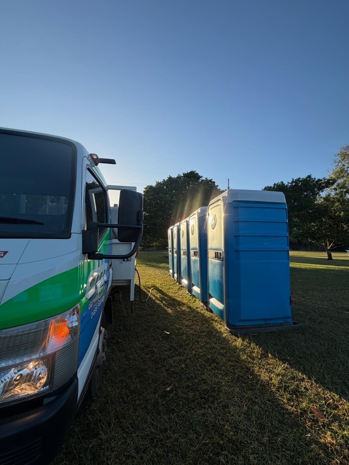 Green and Blue Flatbed Truck Parked Roadside Under a Cloudy Sky — Darwin Toilet Hire in Rosebery, NT