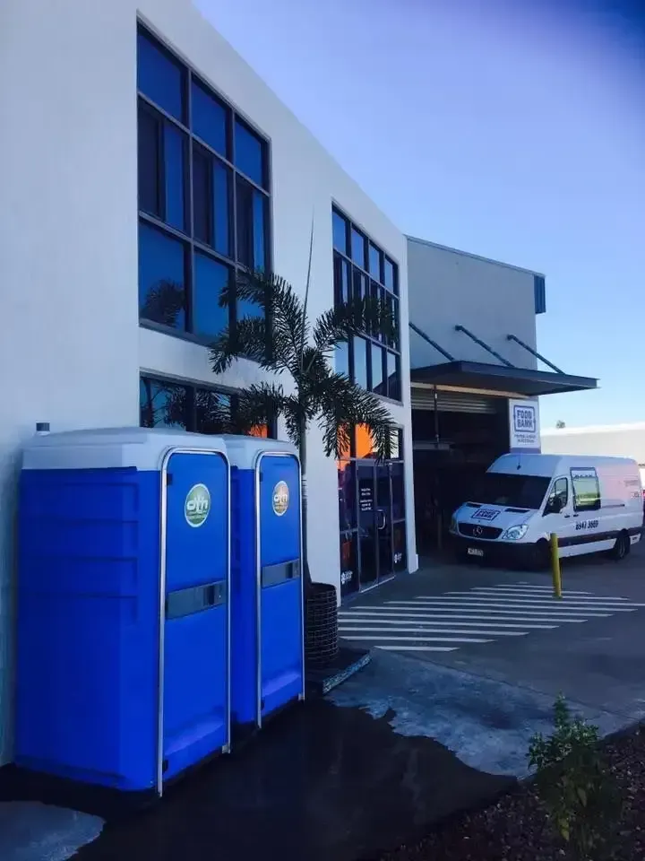 Blue Portable Toilets Beside a Modern Building — Darwin Toilet Hire in Rosebery, NT