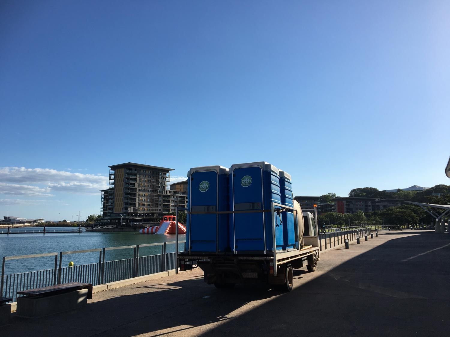 Blue Truck Parked by a Waterfront Walkway Near Buildings Under a Clear Sky — Darwin Toilet Hire in Rosebery, NT