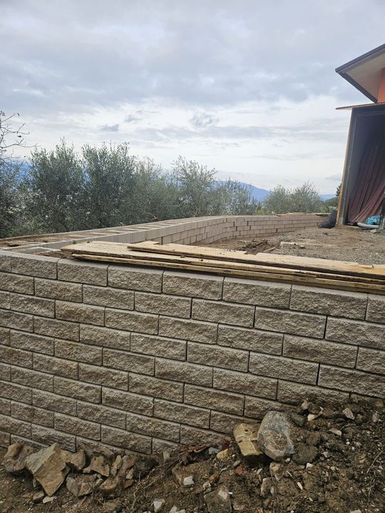 Persona che sostituisce una tegola rossa su un tetto spiovente, con sfondo un cielo azzurro e terso.